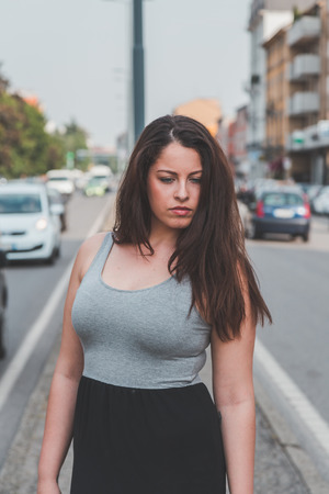 Beautiful young curvy girl in tank top posing in an urban contextの写真素材