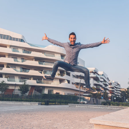 Young handsome man with short hair wearing a bow tie and jumping in the city streets