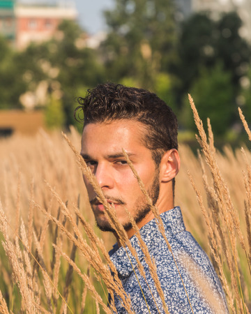 Young handsome man with short hair posing in a fieldの写真素材