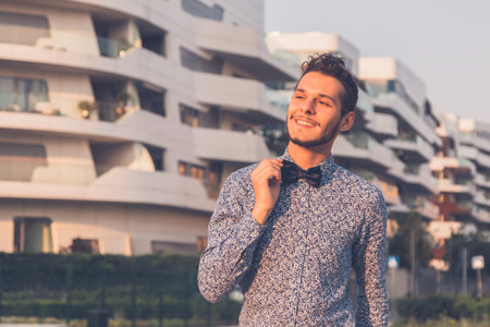 Young handsome man with short hair wearing a bow tie and posing in the city streetsの写真素材