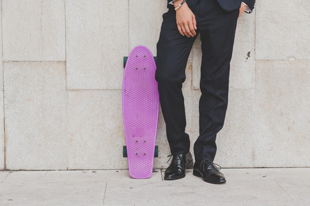 Detail of a young model dressed in dark suit posing with his skateboardの写真素材