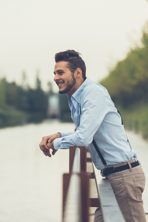 Young handsome man with short hair and beard wearing suspenders and posing in an urban contextの写真素材