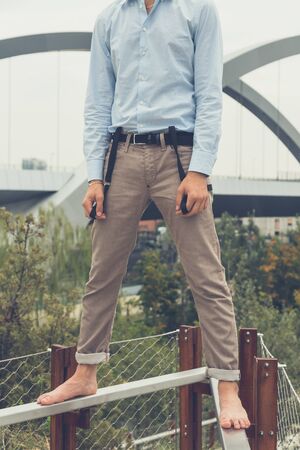Young handsome man with short hair and beard wearing suspenders and posing in an urban contextの写真素材