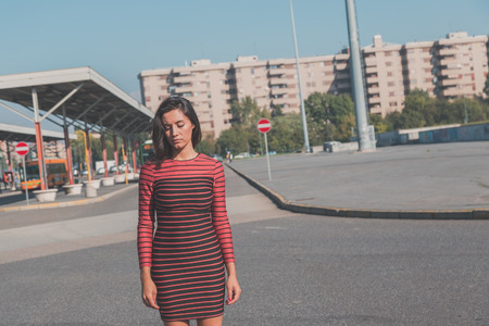 Beautiful young brunette with long hair posing in an urban contextの写真素材