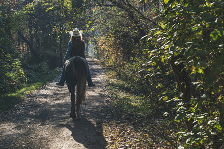 Pretty blonde girl riding her grey horse in the countrysideの写真素材