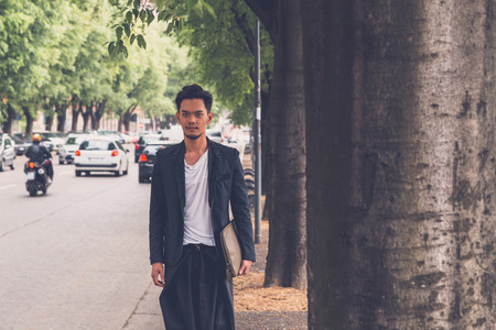 Young handsome Asian model dressed in black posing in the city streetsの写真素材