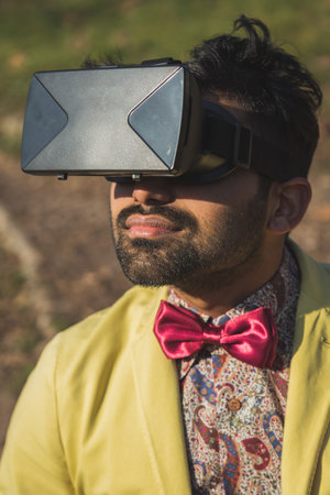 Portrait of an Indian young handsome man wearing virtual reality headset in a city park