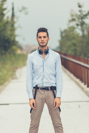 Young handsome man with short hair and beard wearing suspenders and posing in an urban contextの写真素材
