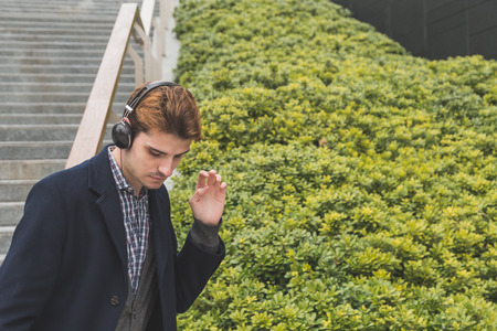 Young handsome man with headphones listening to music in an urban contextの写真素材