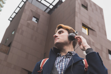 Young handsome man with headphones listening to music in an urban contextの写真素材