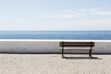 Empty bench in front of the Atlantic Ocean with cloudy sky
