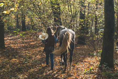 Pretty blonde girl standing by her grey horse in the countrysideの写真素材