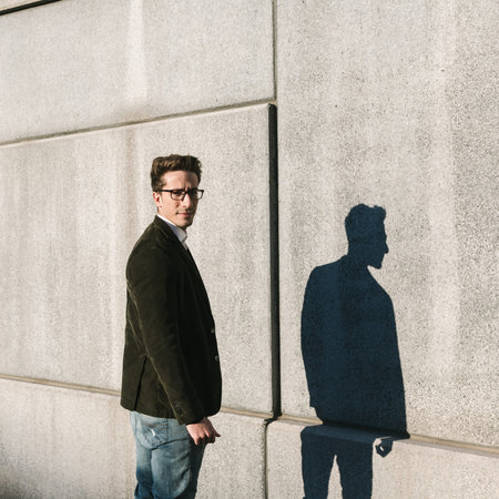 Young handsome man with short hair posing in front of his shadow