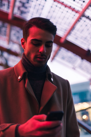 Beautiful young man with short hair texting in an urban contextの写真素材