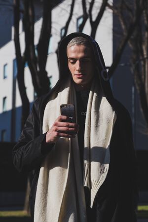 MILAN, ITALY - JANUARY 17: Beautiful model texting outside Armani fashion show building during Milan Men's Fashion Week on JANUARY 17, 2017 in Milan.のeditorial素材