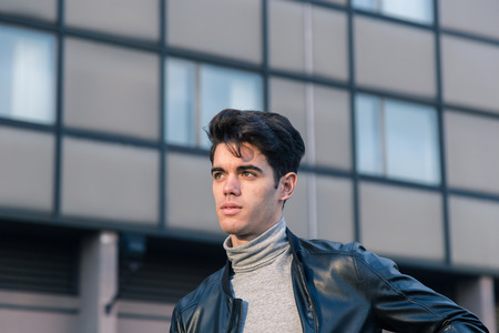 Beautiful young man with short hair posing in an urban contextの写真素材