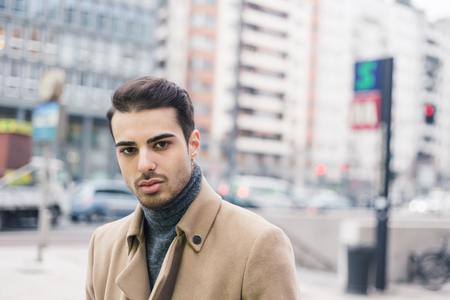 Beautiful young man with short hair posing in an urban contextの写真素材