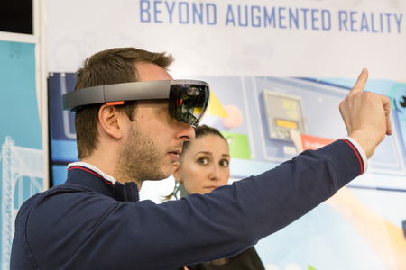 MILAN, ITALY - APRIL 21, 2017: Man tries augmented reality glasses at Technology Hub, international event for innovative and futuristic technologies serving business.のeditorial素材