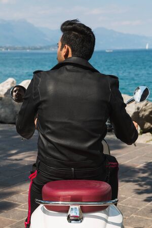 Handsome Indian man posing on a scooter in a vacation context. Street fashion and style.の写真素材