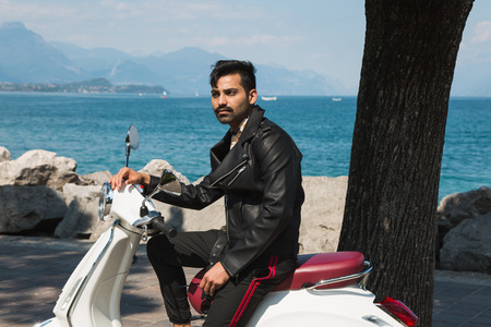 Handsome Indian man posing on a scooter in a vacation context. Street fashion and style.の写真素材