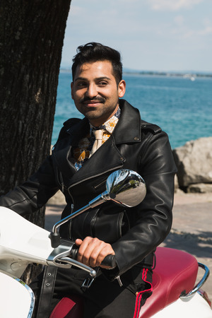 Handsome Indian man posing on a scooter in a vacation context. Street fashion and style.の写真素材