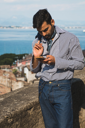 Handsome Indian man texting in a vacation context. Street fashion and style.の写真素材
