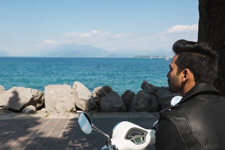 Handsome Indian man posing on a scooter in a vacation context. Street fashion and style.の写真素材