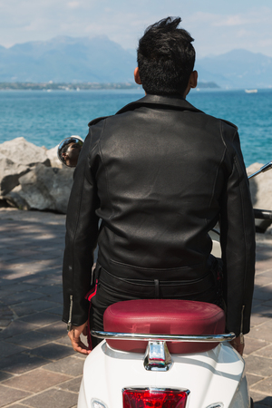 Handsome Indian man posing on a scooter in a vacation context. Street fashion and style.の写真素材