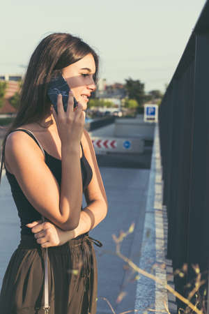 Young beautiful woman with long hair talking on phone in an urban contextの写真素材