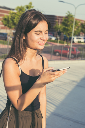 Young beautiful woman with long hair texting in an urban contextの写真素材