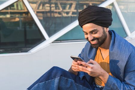 Handsome Indian man texting in an urban context. Street fashion and style.の写真素材