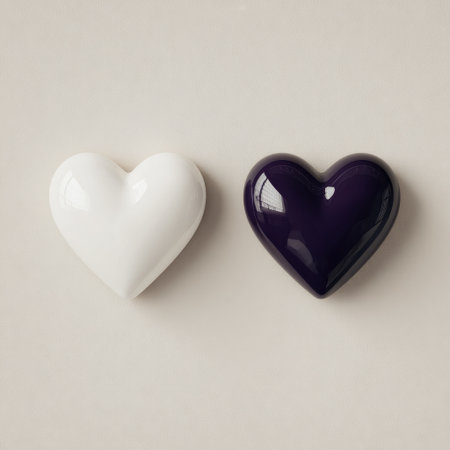 Two glossy, heart-shaped objects, one white, one dark purple, on a neutral backgroundの素材