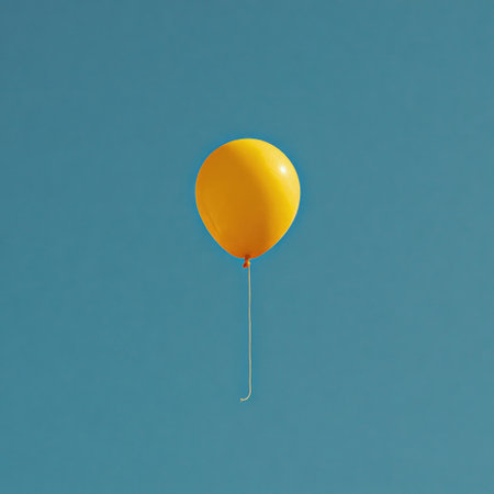 A vibrant yellow balloon suspended against a clear, bright, azure skyの素材