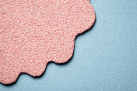 Textured, pink felt with scalloped edge against a light blue backgroundの素材