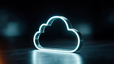 A glowing neon cloud icon is presented against a dark, blurred backdrop. The cloud shape emits a bright, cool light, casting subtle reflections on a textured surface. The image utilizes a shallow depth of field, emphasizing the illuminated form. This graphic could be used in various commercial or editorial contexts related to technology.の素材