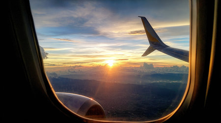 View from the window of a passenger plane during flight at sunset.の素材
