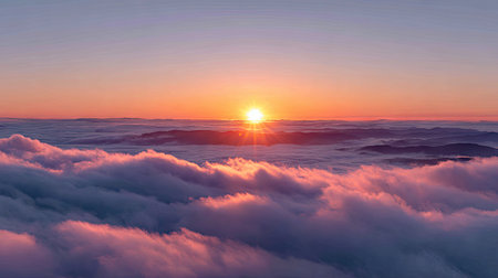 An aerial view presents a vibrant sunrise above a thick blanket of clouds. The scene features soft, diffused lighting with hints of pink and orange, possibly captured at dawn. This idyllic view could be suitable for various editorial and commercial applications, showcasing natural beauty and atmospheric conditions.の素材