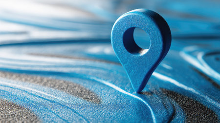 A close-up captures a vibrant blue location pin set on an abstract textured surface with a blurred background. The composition highlights flowing lines and shades of blue. The image suggests concepts related to travel, wayfinding, and business strategies. This visual can be utilized in various commercial or editorial contexts.の素材