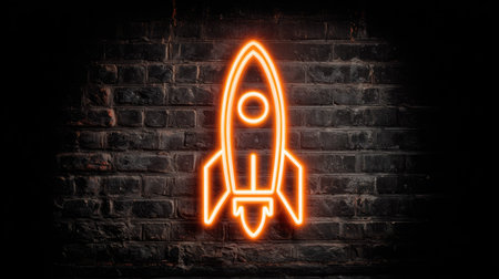 An illuminated neon rocket symbol glows against a dark brick wall backdrop. The image features orange lighting, a close-up perspective, and a textured surface. The style suggests a modern, urban aesthetic suitable for illustrating concepts of innovation, technology, or future-oriented themes. This image could be utilized for various commercial and editorial projects.の素材