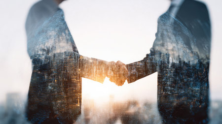 Two individuals in suits shake hands, symbolizing agreement. The image features an overlay of a forest and sunlight, suggesting growth and collaboration. Soft lighting and a blurred background create a feeling of warmth. This image is suitable for various commercial uses, including website design and marketing.の素材