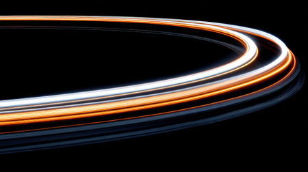 Illuminated trails of light curve across a dark background. The lines exhibit a gradient of warm colors, including orange and white. The composition features sharp focus, suggesting a digital artwork for use in modern design projects. Suitable for visual elements in advertising or presentations.の素材