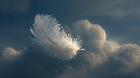A single white feather drifts amidst a textured cloud formation, illuminated by soft lighting. The image showcases a sense of weightlessness and ethereal beauty, with varying shades of blue and white creating depth. Suitable for concepts of tranquility and serenity, this image could be used in various commercial or editorial applications.の素材