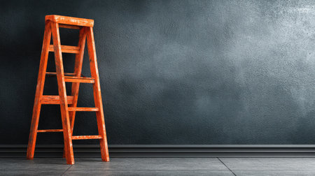 An orange wooden ladder is positioned against a dark textured wall. The composition uses simple lines, with the ladder's structure contrasting against the wall. The image features a minimalist style and likely suitable for a variety of visual communication needs. The setting suggests an indoor environment illuminated by diffused lighting.の素材