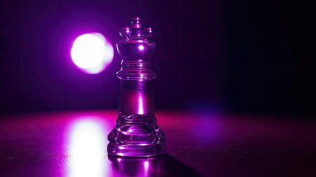 A close-up image features a chess king illuminated by vibrant purple light. The object is positioned on a reflective surface, with a blurred light source adding depth. The composition focuses on the central subject, suggesting uses in design, strategy, and conceptual projects. The image's lighting enhances the visual impact.の素材