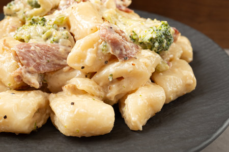 Cream Tteokbokki Korean Rice Cake with Bacon and Broccoli on Black Plateの写真素材