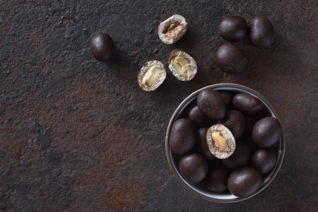 Still life of peanuts in chocolate on an old metal surface top viewの写真素材