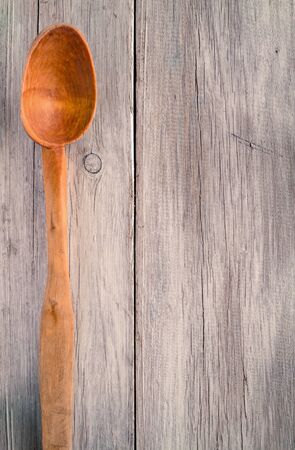 Old wooden spoon on a background of painted boardsの写真素材