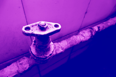Water tap on a very old rusty pipe. Toned image. Duotoneの写真素材
