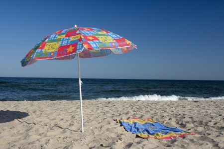 Umbrella on a beach against the dark blue seaの写真素材