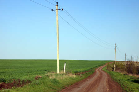 Dirt road passing along a green fieldの写真素材